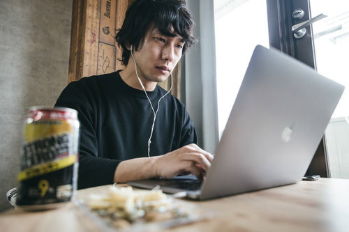 終業10分前、デスクでおつまみとストロングゼロを前に仕事を続ける男性