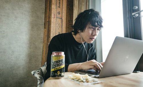 リモート飲みでバーチャル背景を設定しながらストロングゼロを飲む男性