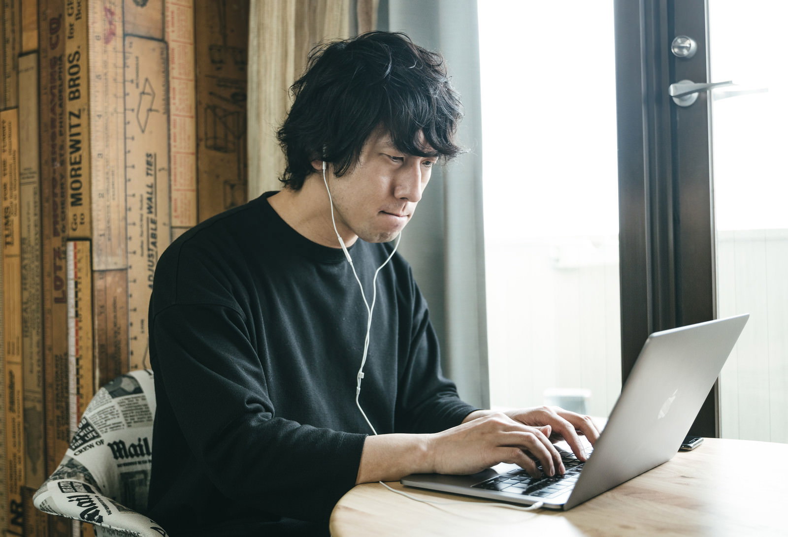 ノートパソコンに向かい困った表情を浮かべる黒いセーター姿の男性［モデル：大川竜弥］