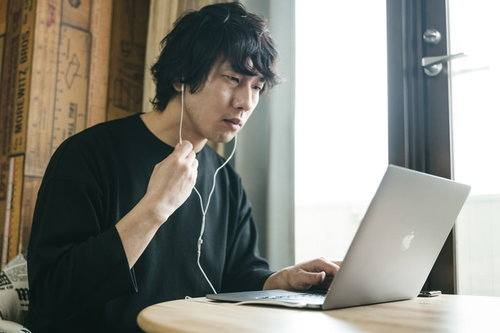 ノートパソコンのリモート会議中に音量を操作する男性