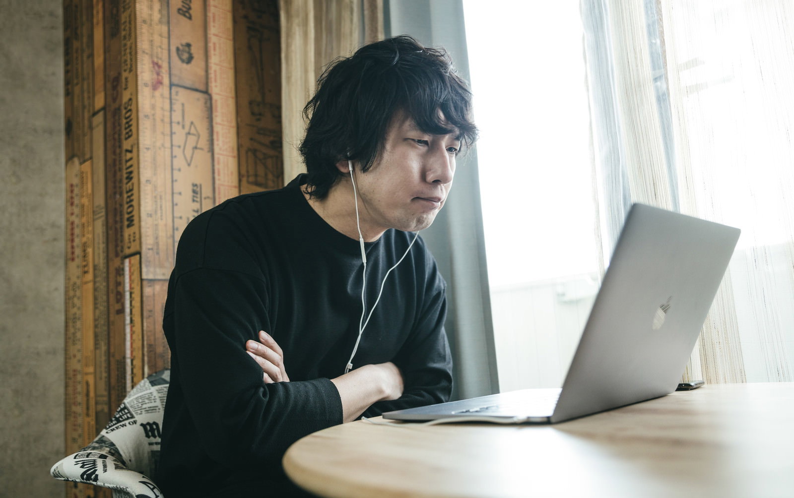 ノートパソコンの前で腕を組み困った表情を浮かべる眼鏡の男性［モデル：大川竜弥］