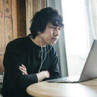 リモートワーク中のコミュニケーションに悩む眼鏡の管理職男性の写真