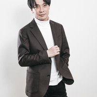 白いタートルネックにブラウンジャケットを羽織る取締役社長の写真