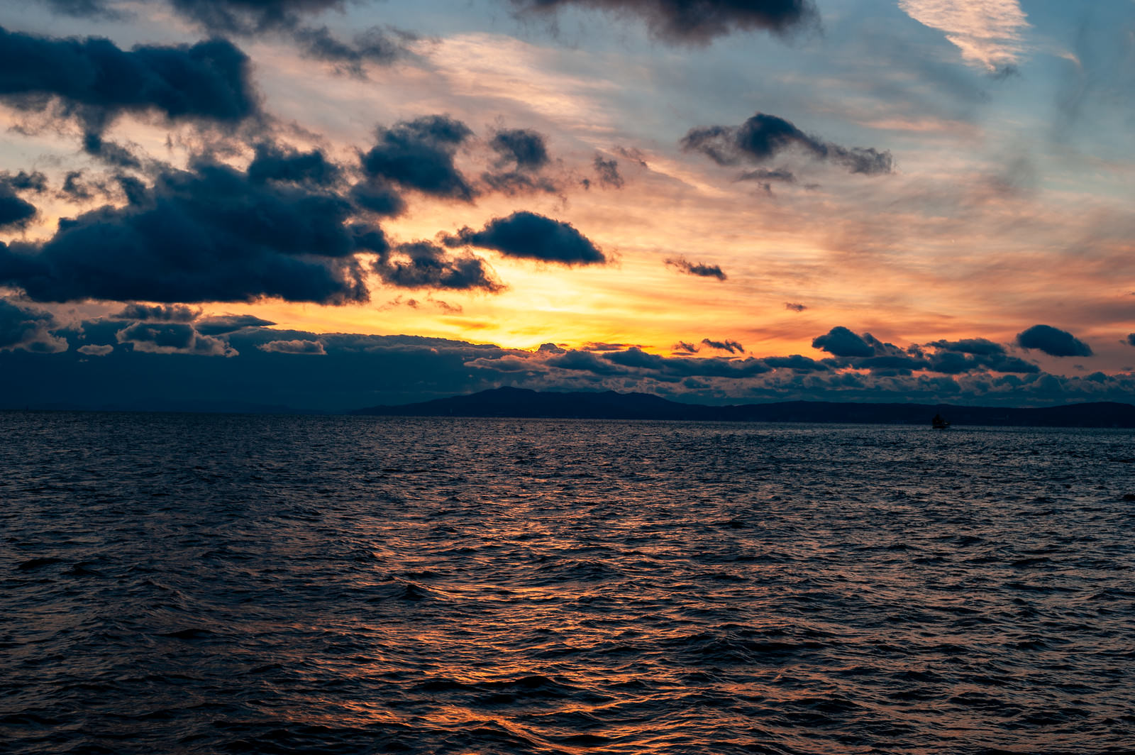 夕焼け空の下で海面にさざ波が立つ夕暮れの風景
