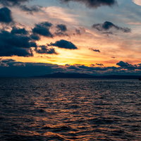夕暮れ時の海面に映る夕焼けとさざ波が輝く風景の写真