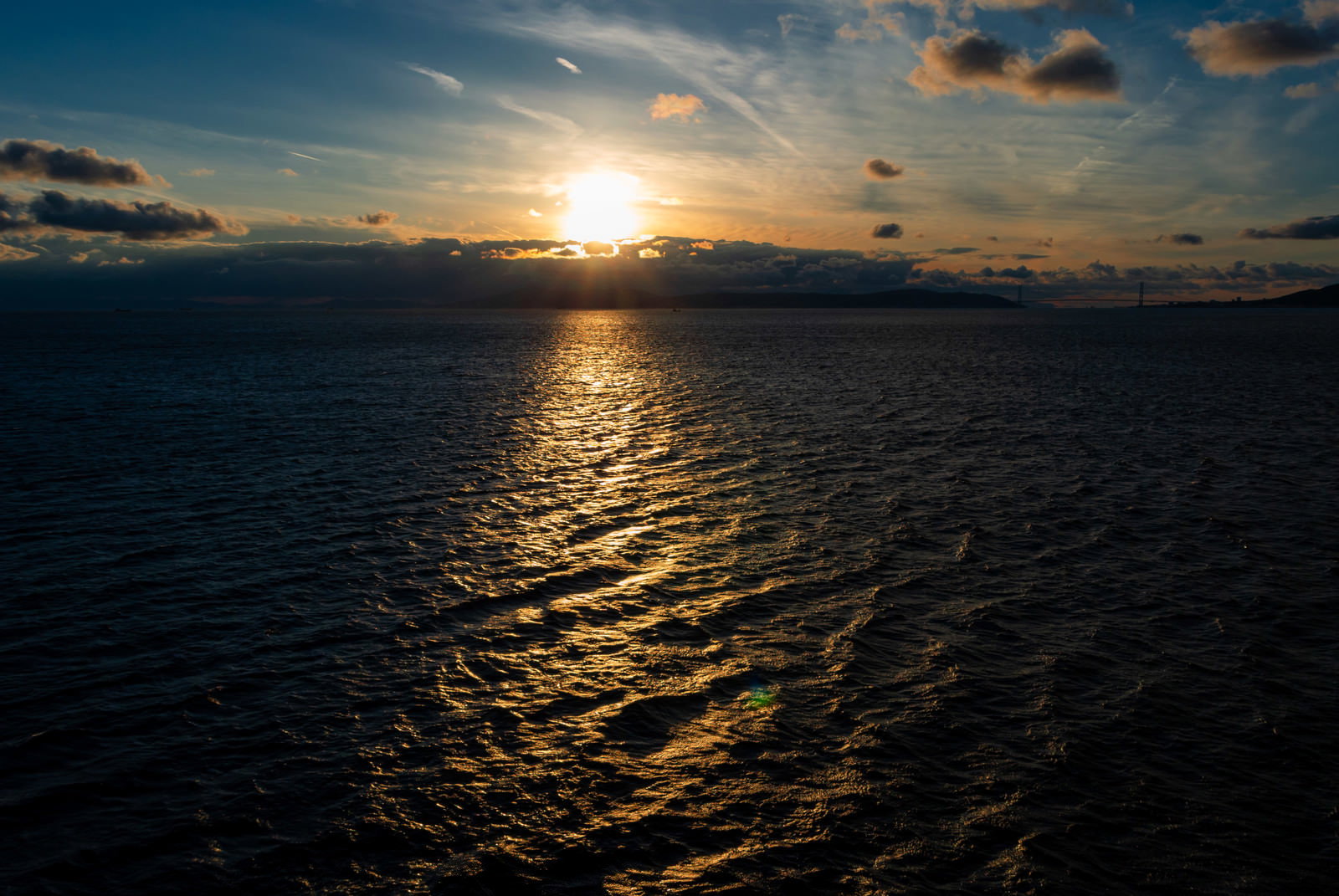 海面のさざ波に夕日の光が反射して輝いている夕暮れの風景