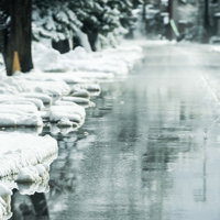 雪国の道路脇から噴出する消雪システムの様子の写真