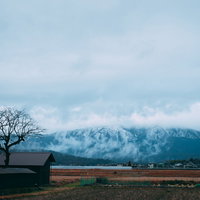 雪化粧した山々の頂上が雲に隠れた雪国の冬景色の写真