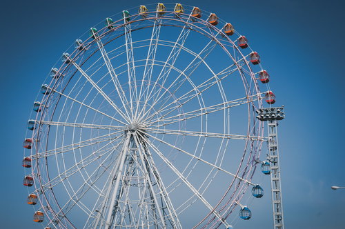 青空にそびえる白い大観覧車、晴天の遊園地