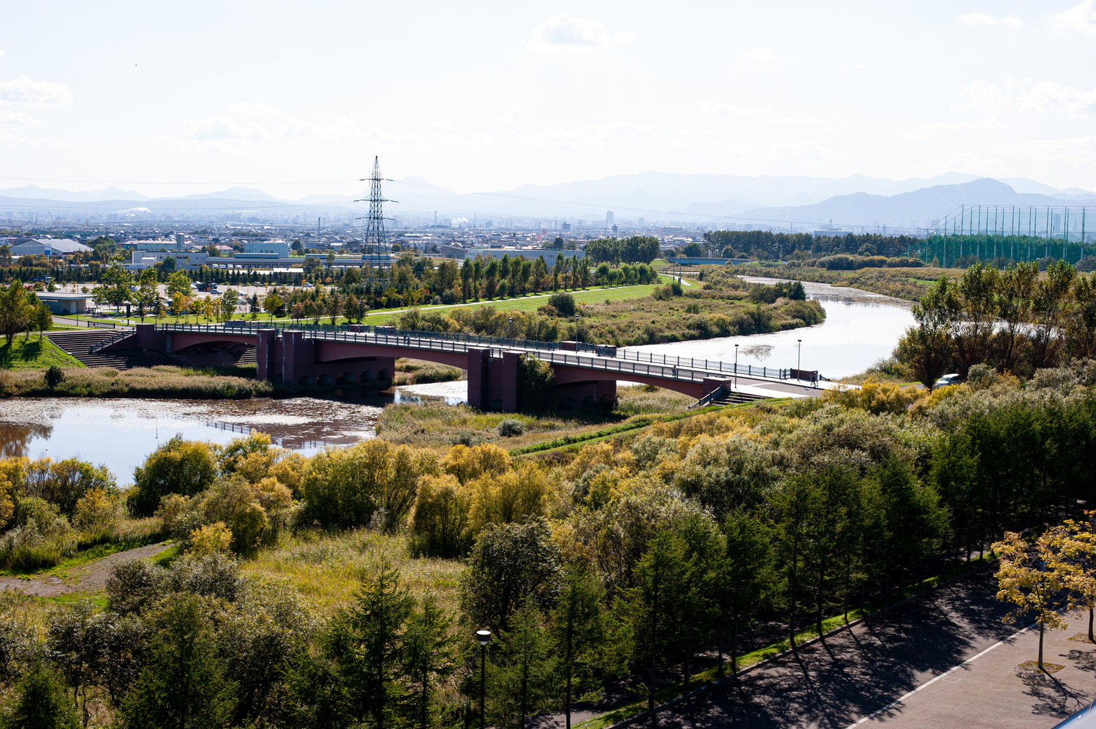 モエレ沼公園の丘から眺める蛇行する川と橋、遠方の街並み