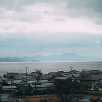 琵琶湖と瓦屋根の家が立ち並ぶ大津市の町並みの写真