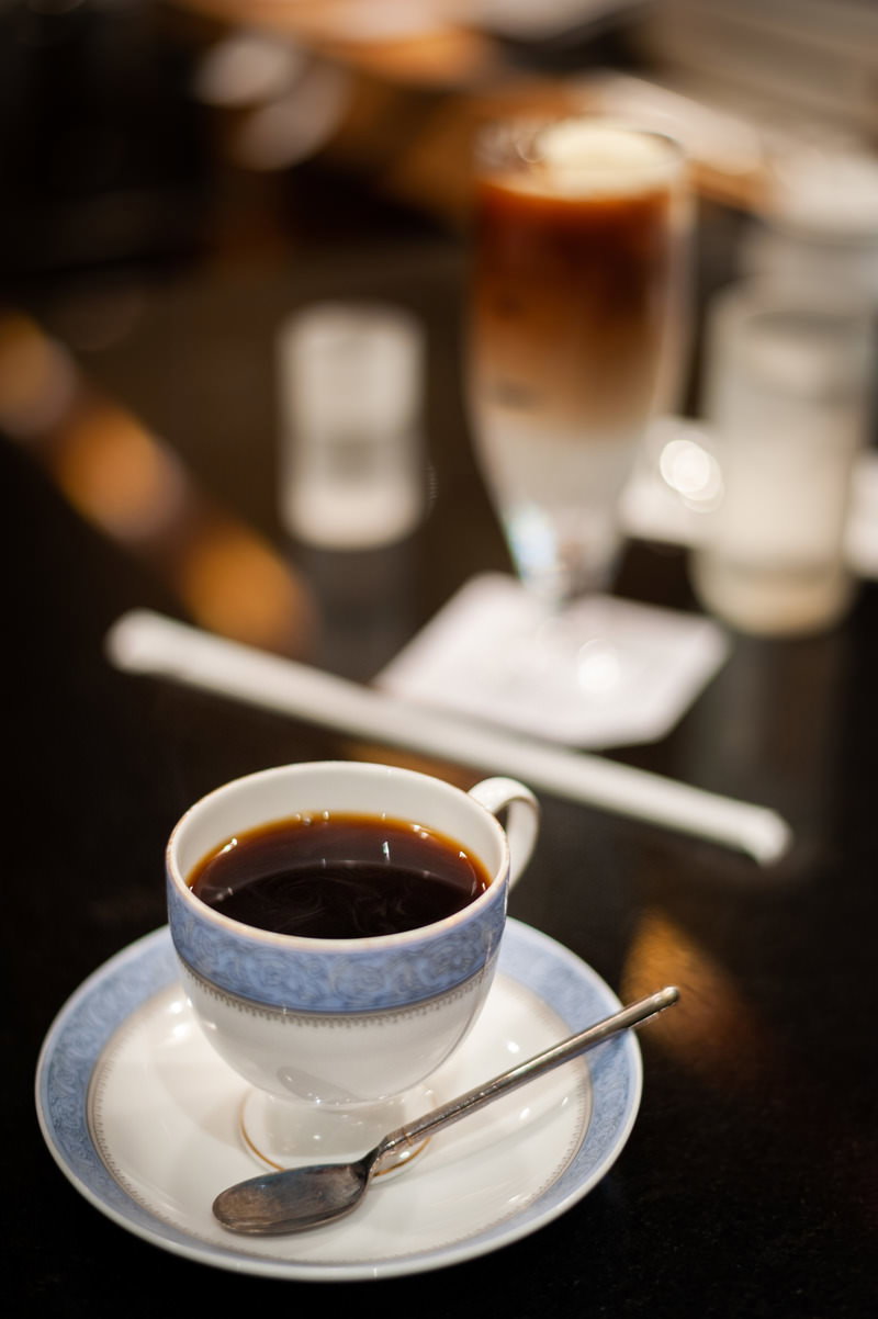 白いカップに入ったホットコーヒーが置かれた喫茶店のテーブル