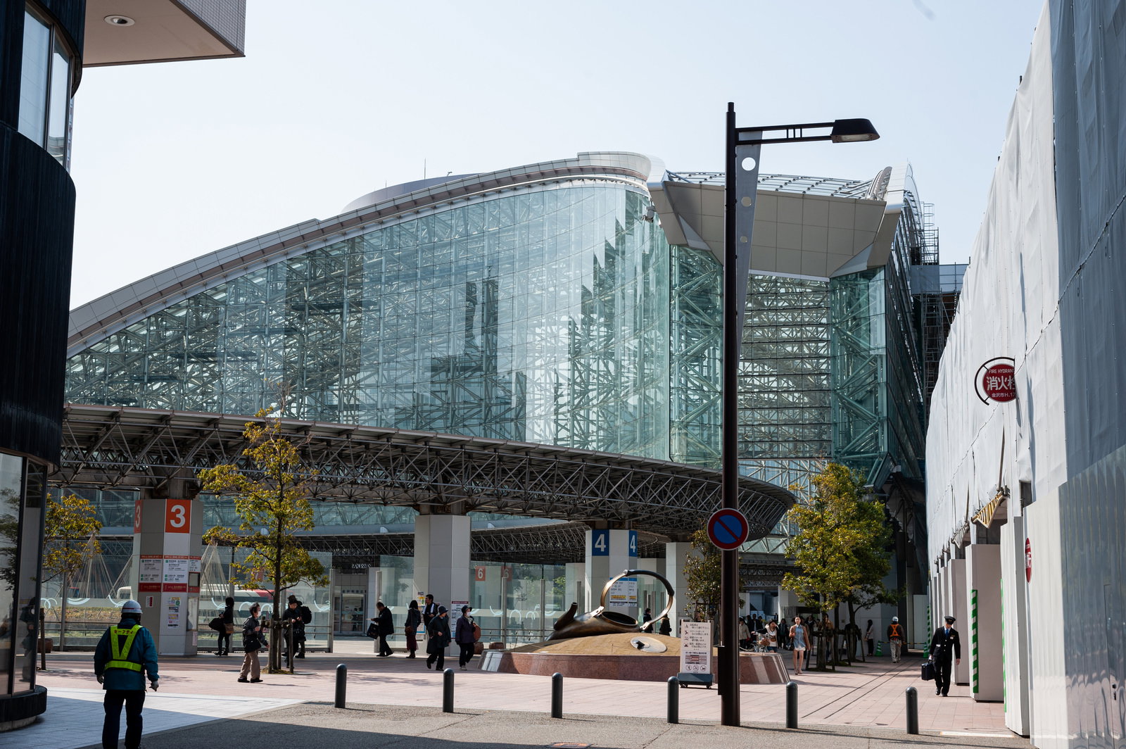 ガラス張りの現代的な建物と整備されたバス乗り場がある金沢駅の駅前風景