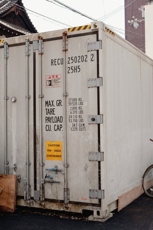 白い海上コンテナのドア、金属ハンドルと警告表示