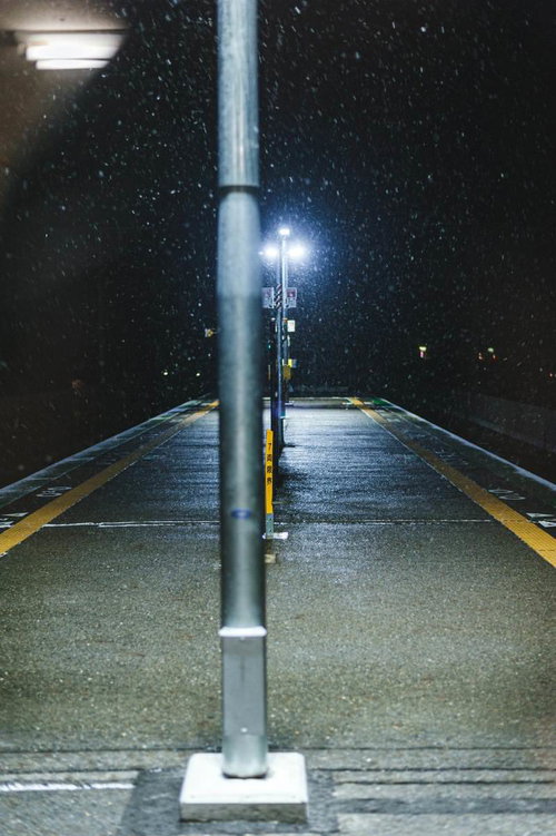 降雪中の深夜駅ホーム、街灯に照らされた静寂の空間