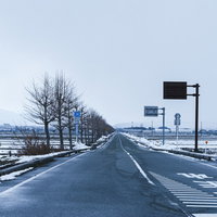 どこまでも続く雪化粧の車道と冬景色の写真