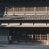 格子戸と木製看板の古い木造民家の写真