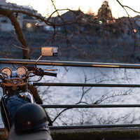 川沿いの金網柵前に停めた青いバイクの写真