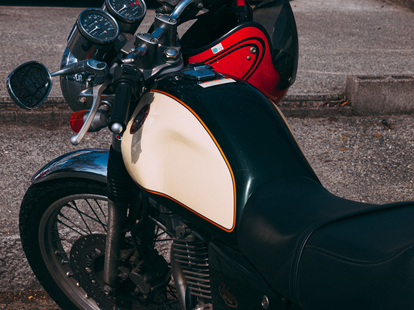 Black Yamaha SR400 motorcycle with a red helmet on its fuel tank