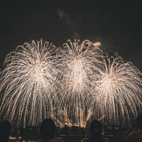 夜空に上がる打上げ花火と鑑賞する観客たちの写真