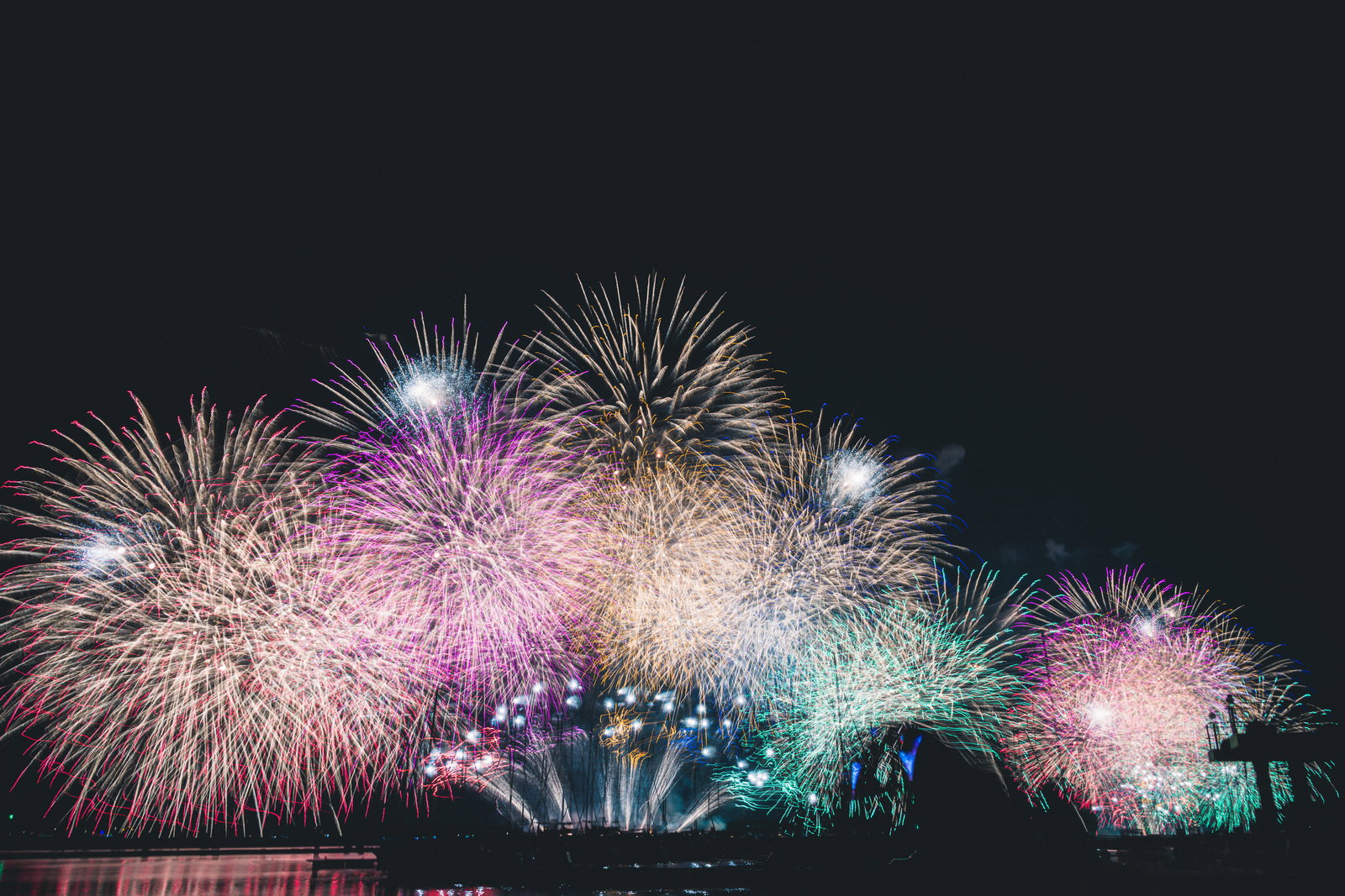 夜空に咲く色とりどりの打ち上げ花火が光る様子