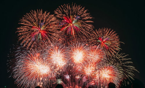 夜空に炸裂する赤とオレンジ色の打上花火が放射状に広がる壮大なシーン