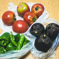 直売所で買った採れたて野菜と木製テーブルの写真