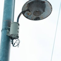 老いた街灯と青緑色の電柱の都市風景 - 昼間の屋外照明インフラの写真