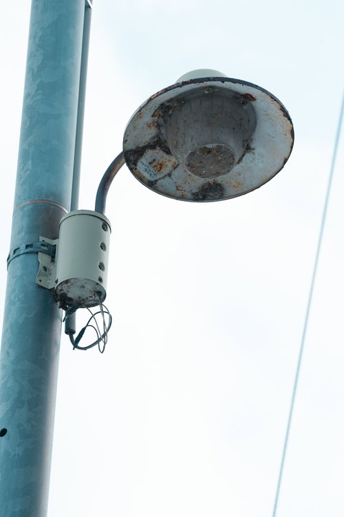 老いた街灯と青緑色の電柱の都市風景 - 昼間の屋外照明インフラ