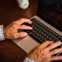MacBookを使うおじいさんの手の写真
