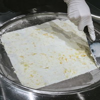 白い手袋でスプーンを使ってロールアイスを作る調理の様子の写真