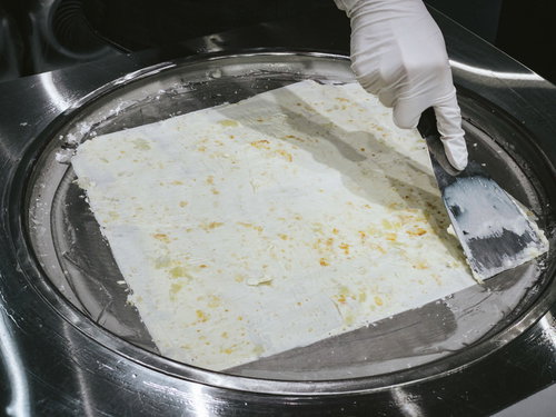 白い手袋でスプーンを使ってロールアイスを作る調理の様子