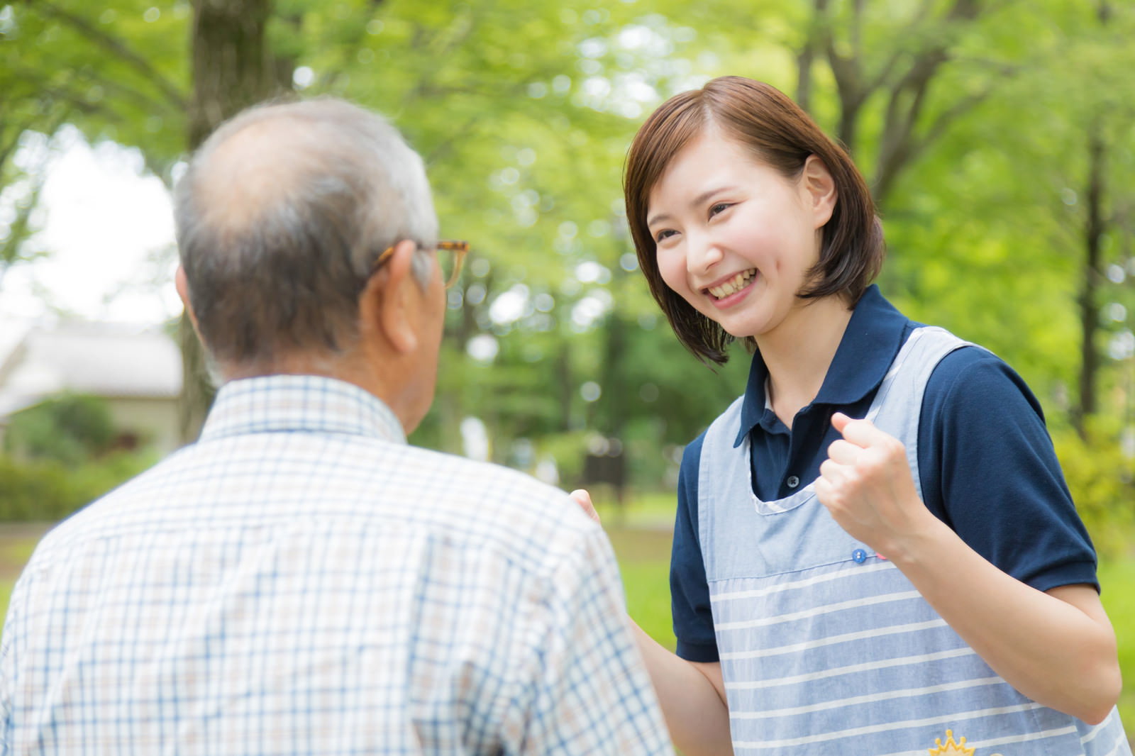 屋外で高齢者男性と笑顔で会話する女性介護士［モデル：まーちゃん yumiko］