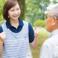 公園で高齢男性に笑顔で励ます女性介護士とのコミュニケーションの写真