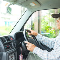 ハンドルを握りしめる高齢者の男性の運転風景の写真