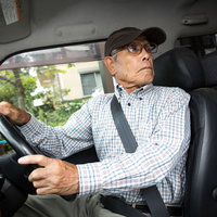 駐車中にアクセルとブレーキを間違えて慌てる高齢者ドライバーの写真