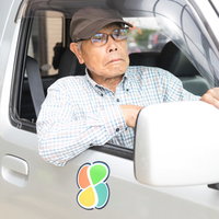 渋滞で前が進まずイライラする運転席の高齢男性ドライバーの写真