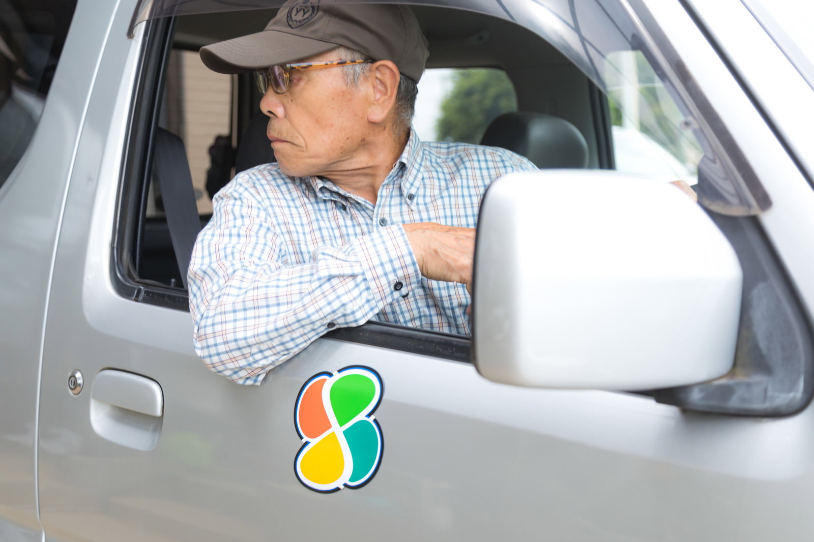 車内で後方を振り返って目視確認している高齢男性ドライバー［モデル：まーちゃん］
