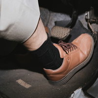 黒い靴を履いてアクセルペダルを踏む高齢者の足元の写真