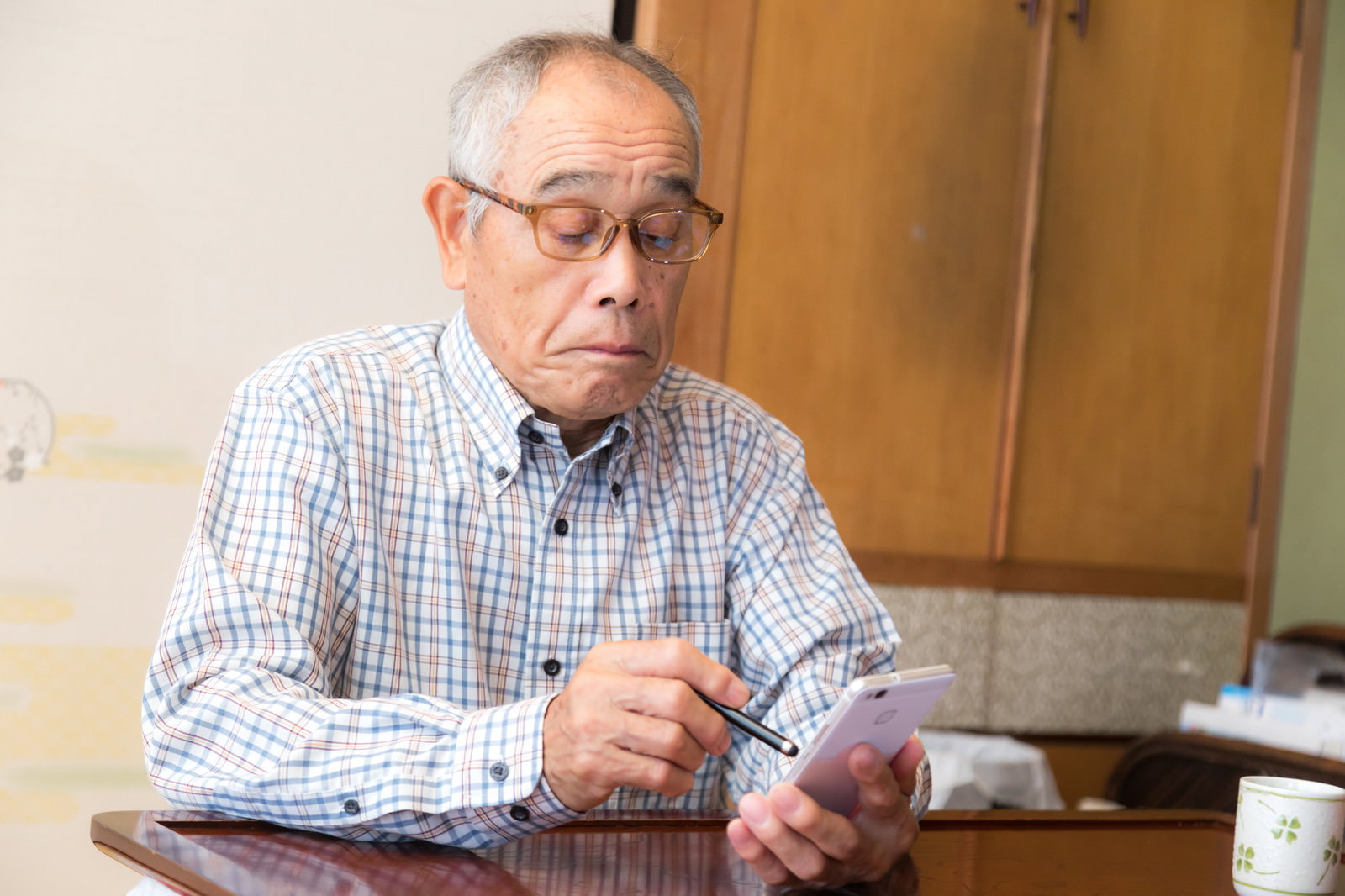 眼鏡をかけたおじいさんがスマートフォンを操作している様子［モデル：まーちゃん］
