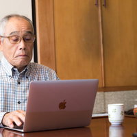 株価のチェックに余念がない高齢者の男性の写真