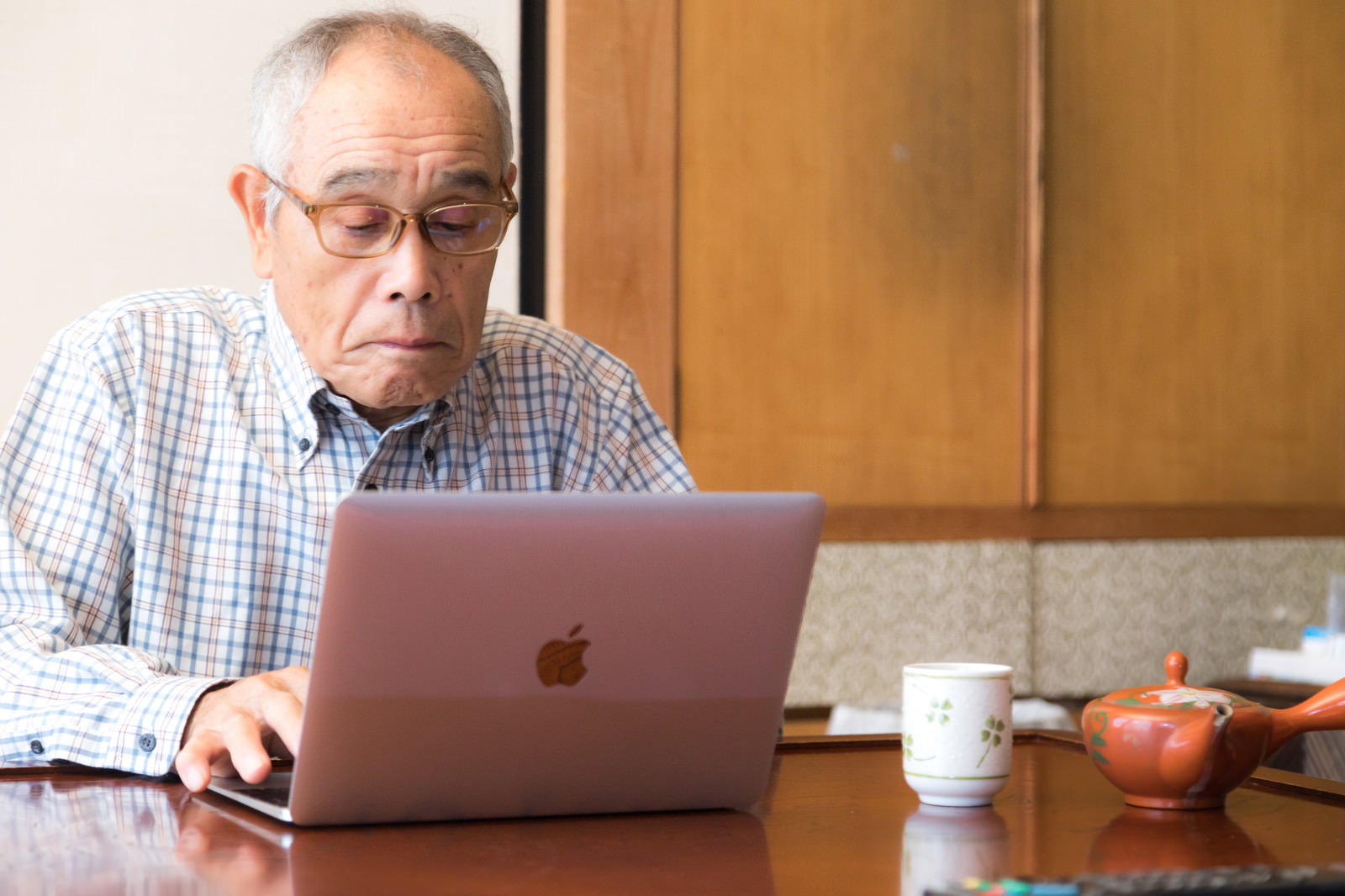 眼鏡の高齢男性がMacBookを操作している［モデル：まーちゃん］