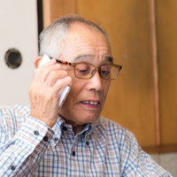 電話に出るじっちゃんの真剣な表情で詐欺被害への警戒を示すの写真