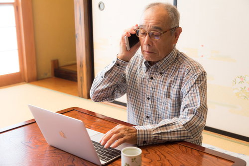 スマートフォンで打ち合わせをする高齢者エンジニア