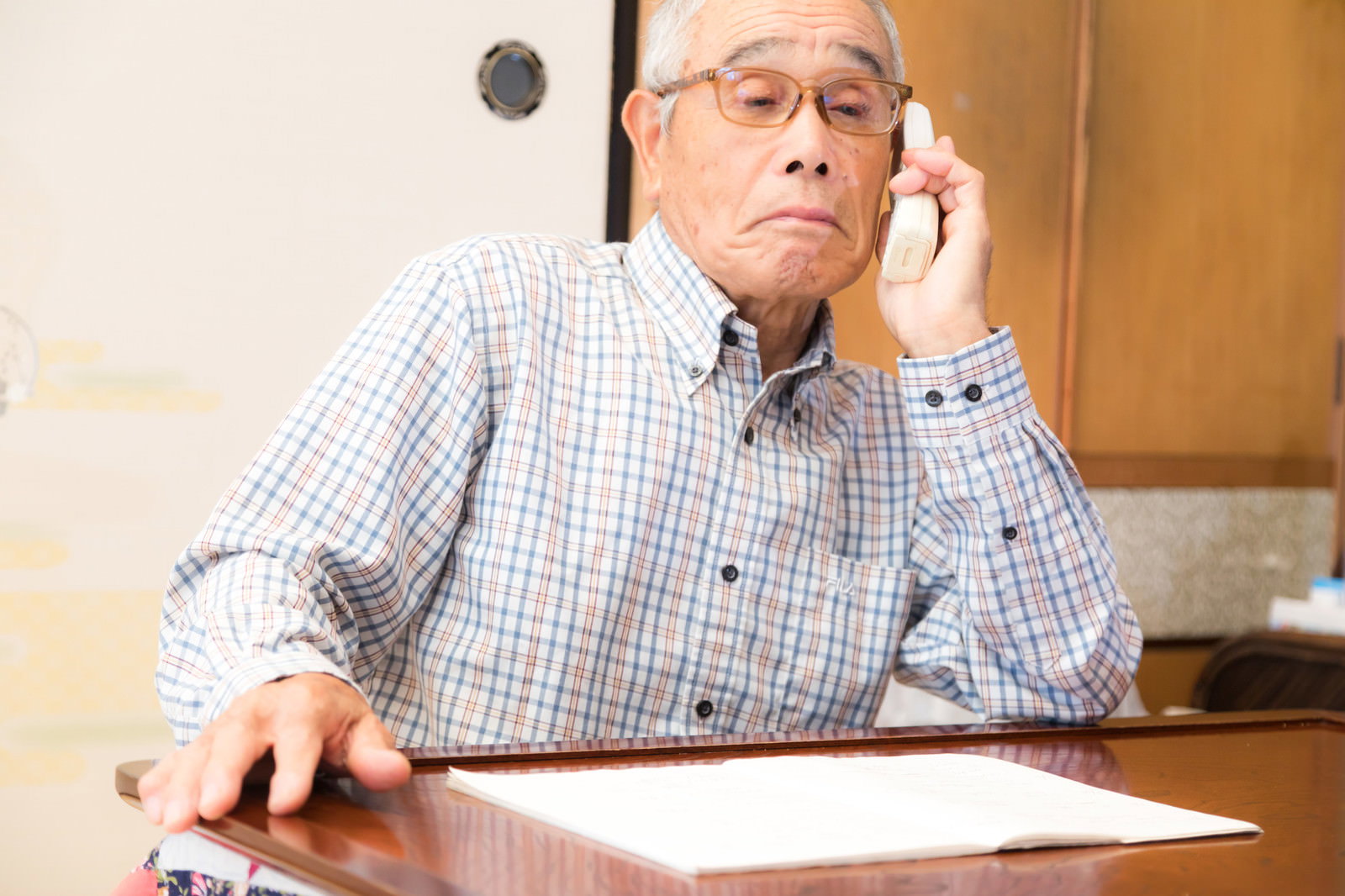 眼鏡をかけた高齢の男性が電話で通話している様子［モデル：まーちゃん］