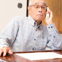 息子を装った電話に出てしまう高齢者男性の不安な表情の写真
