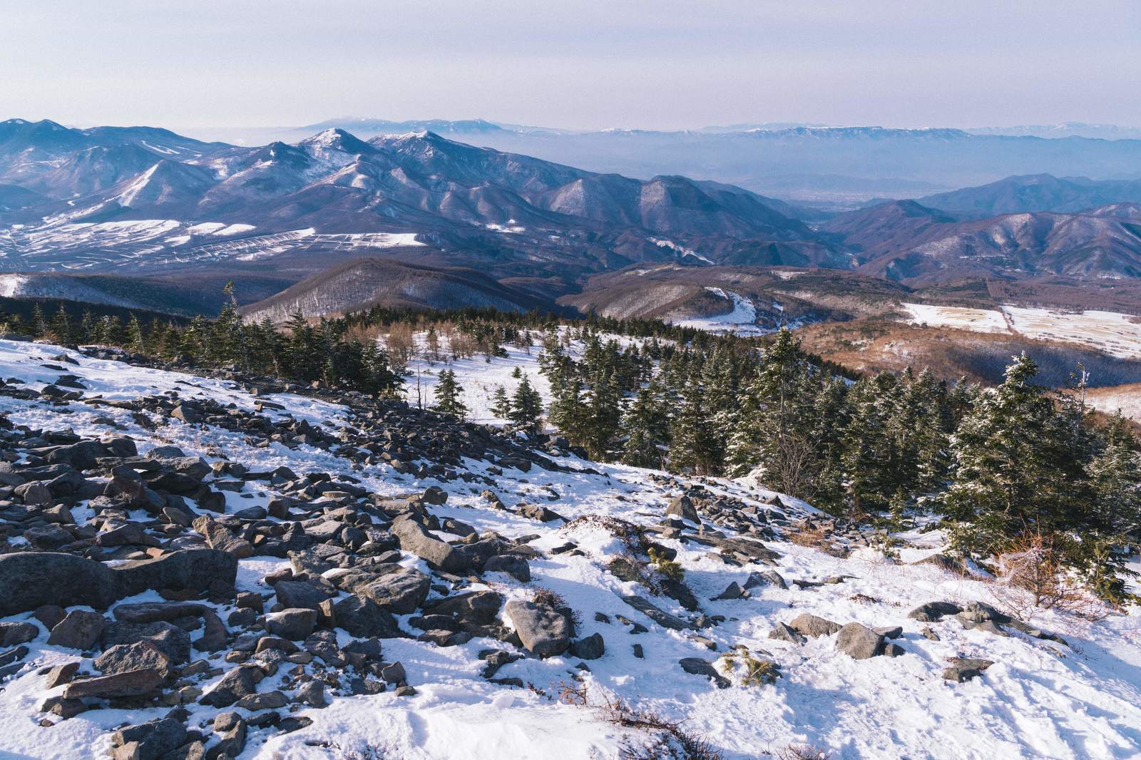 四阿山中腹から眺める雪に覆われた山々と針葉樹林の冬景色