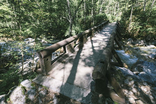上高地から槍ヶ岳へ繋ぐ丸太囲いの木製橋と清流の登山道風景