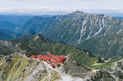 赤い屋根の槍ヶ岳山荘と笠ヶ岳の遠景、北アルプスの雄大な山々