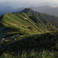 夜明けの飯豊本山からダイクラ尾根を眺める山岳風景の写真